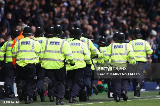 Police officers run to reinforce colleagues at the other end of the ground after trouble breaks out between fans during the English FA Cup fourth...