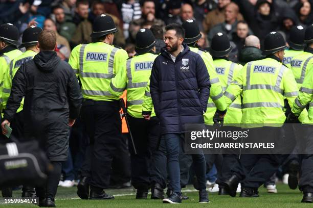 West Bromwich Albion's Spanish head coach Carlos Corberan walks away as police officers reinforce colleagues at the other end of the ground after...