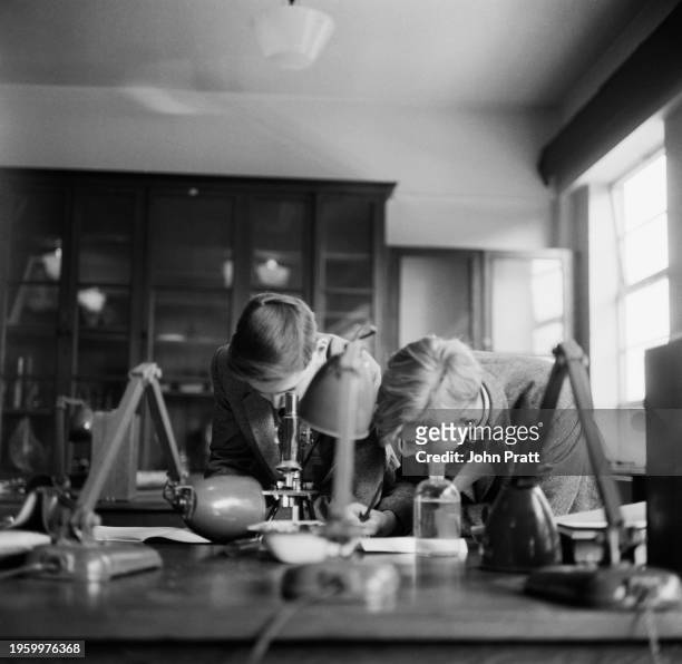 Boy looking through a microscope while another boy is writing during a biology lesson at St Benedict's School in Ealing, London, October 1962. St...