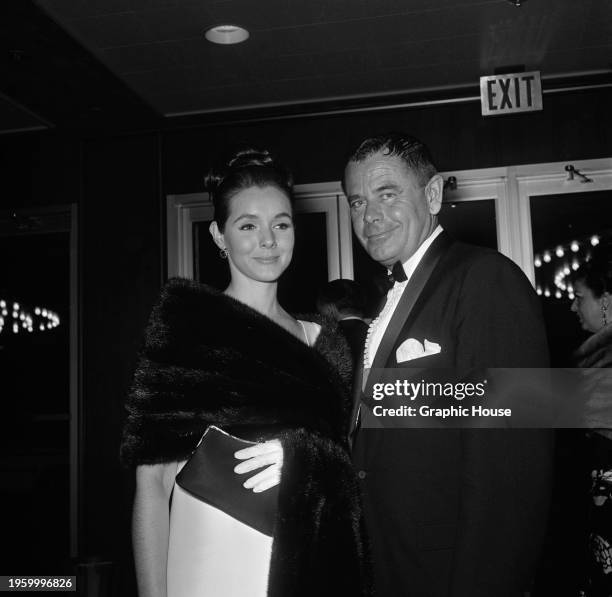 American actress Kathryn Hays, wearing a white outfit with a fur wrap, and her husband, Canadian-American actor Glenn Ford, who wears a tuxedo over a...
