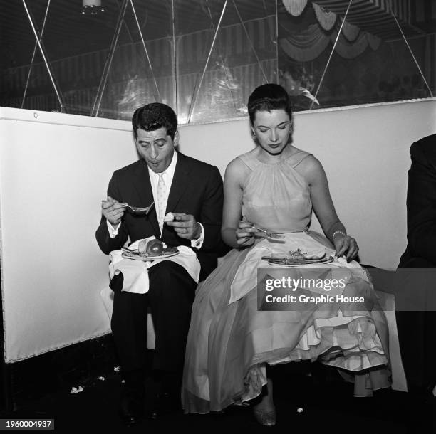 American actor and television host Hal March and his wife, American actress Candy Toxton eating food from plates on their laps, at a party hosted by...