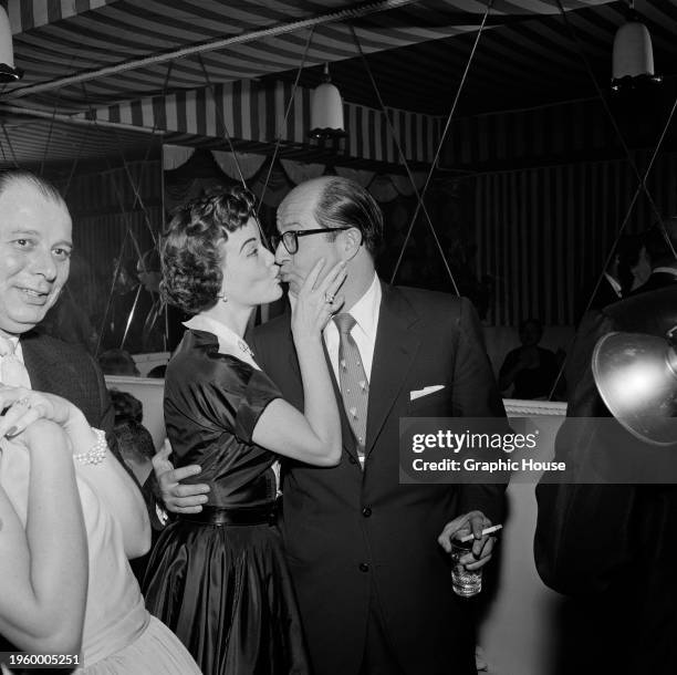 American actress and singer Nanette Fabray kisses American comedian and actor Phil Silvers at a party, United States, 6th March 1956. The party was...