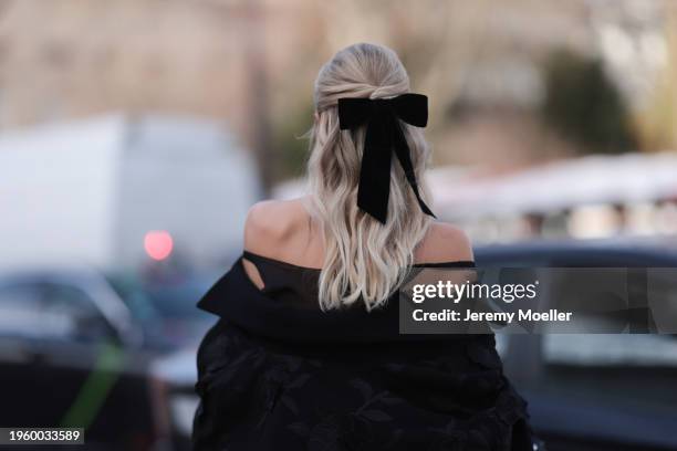 Leonie Hanne is seen wearing a black off-shoulder dress with wide sleeves, black overknees, silver creoles by Tiffany & co. A black handbag with...