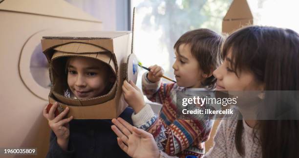 children doing home activity at home, they are painting their spacet helmets made of cardboard. - rpg maker stock pictures, royalty-free photos & images