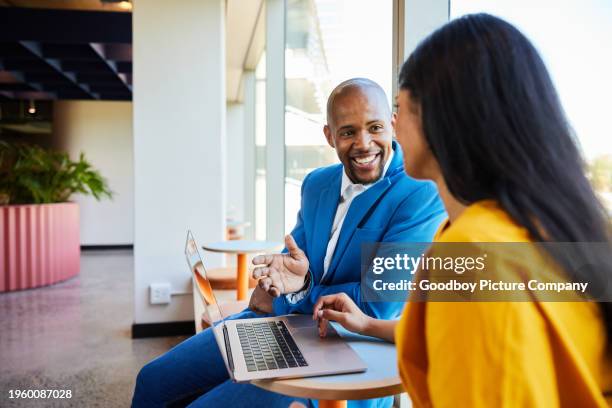 smiling diverse businesspeople talking over a laptop in an office hallway - business meeting stock pictures, royalty-free photos & images