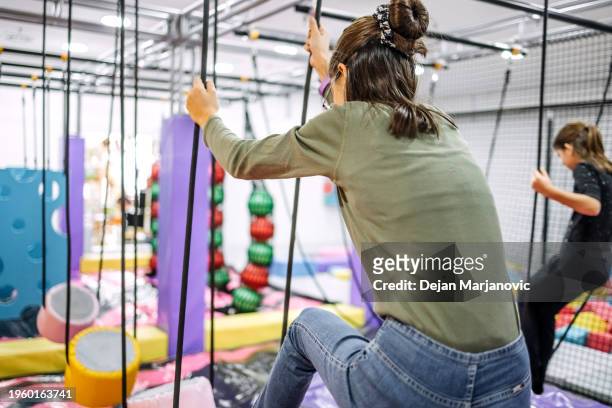 kids having fun at indoor playground hanging on rope - mission court grip stock pictures, royalty-free photos & images