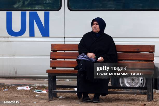 Displaced Palestinian woman sits on a bench as she waits outside a clinic of the United Nations Relief and Works Agency for Palestine Refugees in...