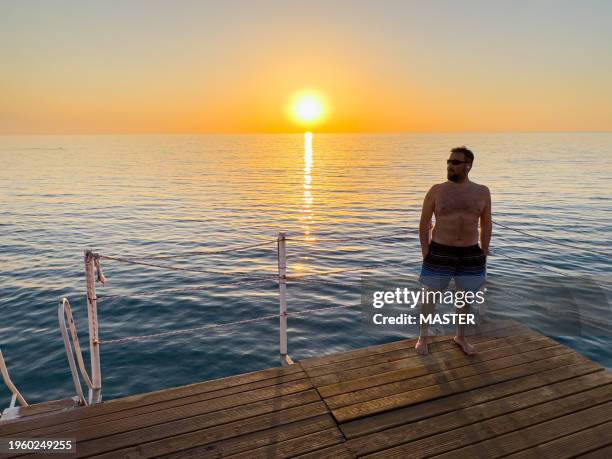 man standing onbeach pier in alanya, turkiye - swimming shorts stock pictures, royalty-free photos & images