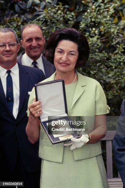 Lady Bird Johnson holding a brooch in the East Garden of the White House, Washington, June 1st 1967. The ornament contains a semi-precious stone from...