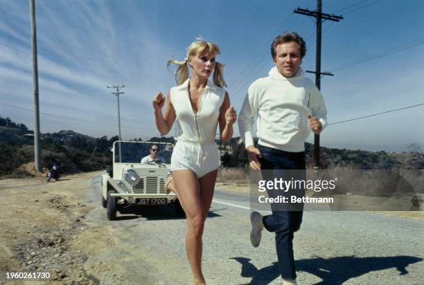 German actress Elke Sommer running along a roadside in Los Angeles, California, February 27th 1967. She is training for an upcoming role as an...