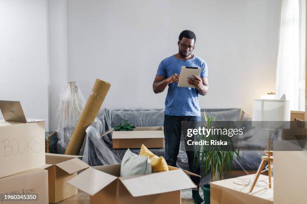 new beginnings. man using tablet in his new home - to do list stock pictures, royalty-free photos & images
