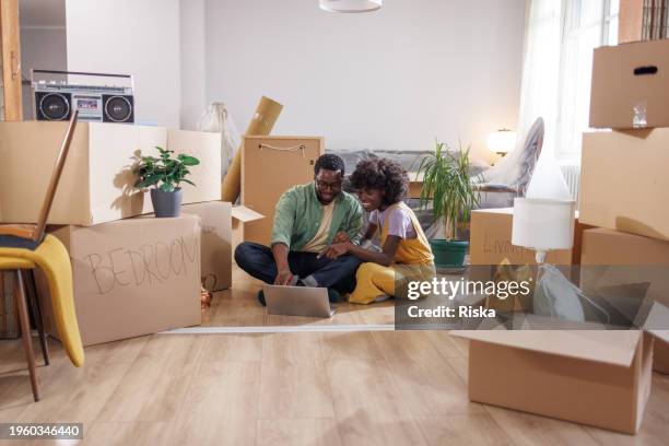 new homeowners - young couple arranging home moving services online with a laptop - milestone stockfoto's en -beelden