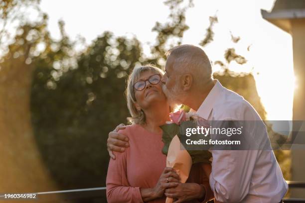 romantisches reifes paar, das während der goldenen stunde bindungsmomente auf dem balkon hat - hochzeitstag stock-fotos und bilder