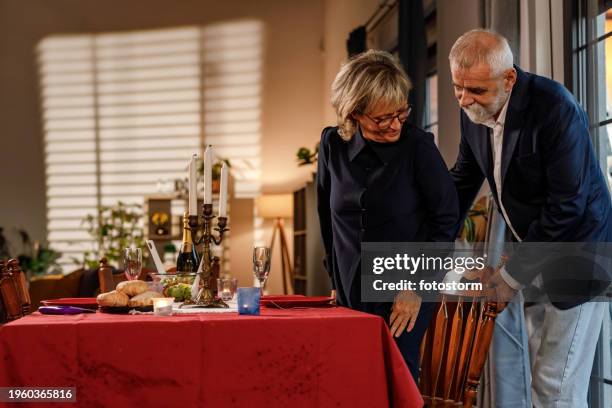 chivalrous man pulling the chair for his wife during a romantic dinner date - charming stock pictures, royalty-free photos & images