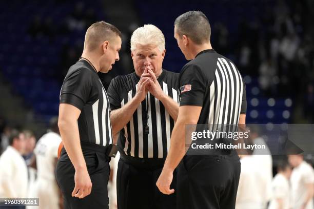 Referees Eric Curry, Brooks Wells, and Owen Scott discuss a call during a college basketball game between the Wisconsin Badgers and the Penn State...