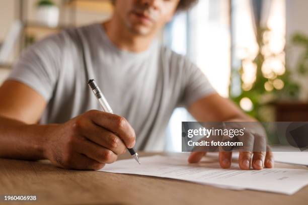 homme assis à table, examinant des documents et signant des contrats - document juridique photos et images de collection