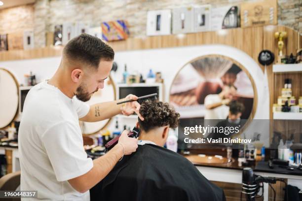 barber giving a haircut in his shop - mens hair styling stock pictures, royalty-free photos & images