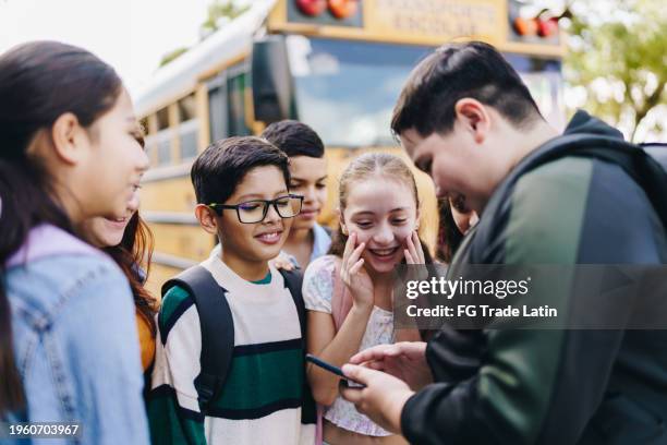 child student friends watching a viral video on mobile phone outdoors - alpha males stock pictures, royalty-free photos & images