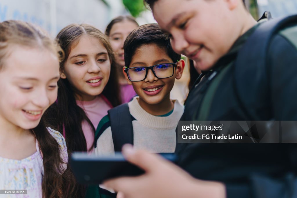Child friends watching a video on mobile phone outdoors
