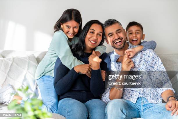 loving happy family portrait sitting on the sofa at home. the children are embracing their parents. - ethnicity stock pictures, royalty-free photos & images