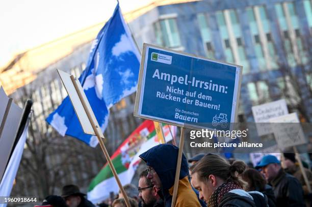 January 2024, Saxony-Anhalt, Magdeburg: Participants at the rally on Cathedral Square hold up a sign reading "Traffic light madness: Not on the backs...