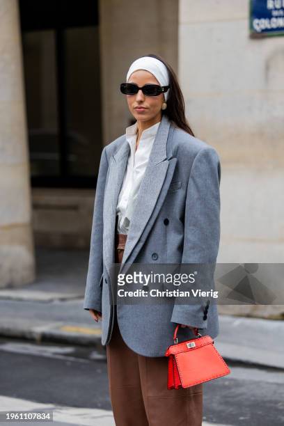 Bettina Looney wears white head band, brown pants, grey oversized blazer, red bag, white blouse outside Fendi during the Haute Couture Spring/Summer...