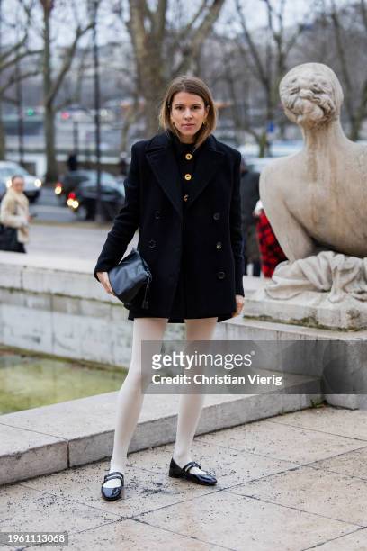 Monica de La Villardiere wears black double breasted jacket, white tights, black bag outside Patou during the Haute Couture Spring/Summer 2024 as...