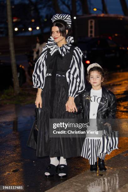 French singer Soko with her child wears black skirt, top striped black white blouse outside Patou during the Haute Couture Spring/Summer 2024 as part...