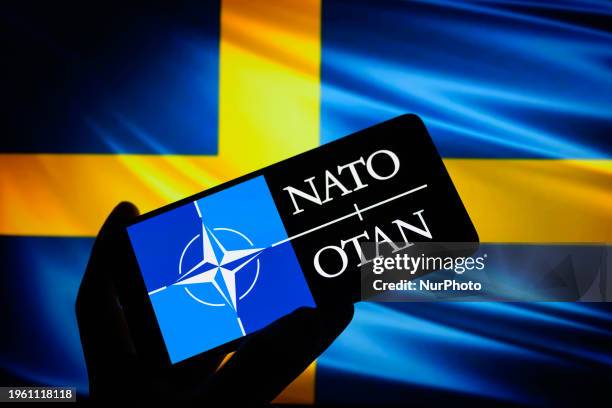 The NATO - OTAN logo is being displayed on a smart phone with the flag of Sweden in the background, in this photo illustration taken in Brussels,...