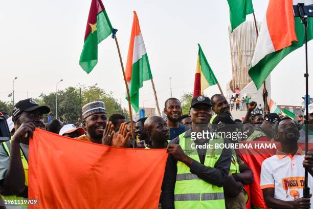 Supporters of the Alliance Of Sahel States hold up flags as they celebrate Mali, Burkina Faso and Niger leaving the Economic Community of West...