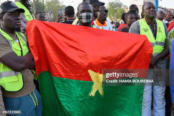 Supporters of the Alliance Of Sahel States hold up a Burkina Faso Flag as they celebrate Mali, Burkina Faso and Niger leaving the Economic Community...