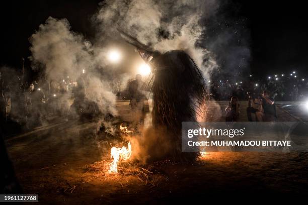 Performer wearing the traditional kumbo mask, a mythological figure of the Jola tribe dressed with palm leaves, whirls in fire during the kankurang...