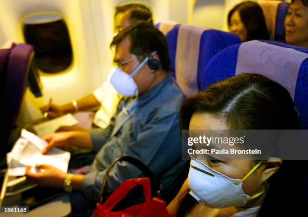 Passengers on a Singapore Airlines flight wear masks to protect against the Severe Acute Respiratory Syndrome virus April 30, 2003 between Singapore...