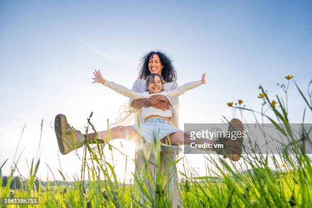mother spinning daughter in field - spring season photos et images de collection