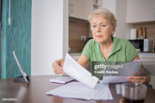 senior woman going through paperwork - woman calculator stock pictures, royalty-free photos & images