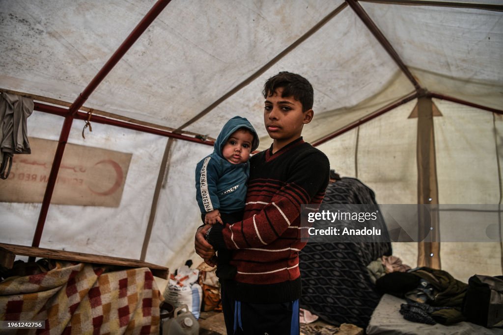 14-year-old Palestinian Mohammed El-Yazici parents his baby brother in Rafah