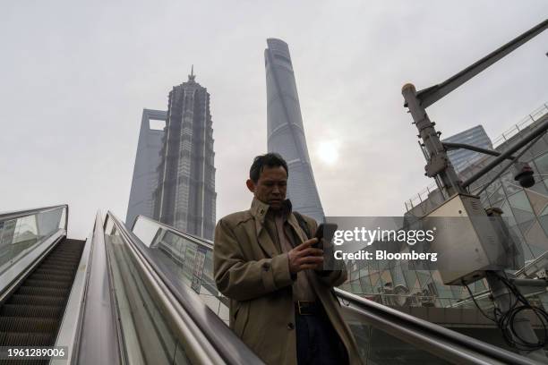 Pedestrian rides an escalator in Pudong's Lujiazui Financial District in Shanghai, China, on Monday, Jan. 29, 2024. China will halt the lending of...