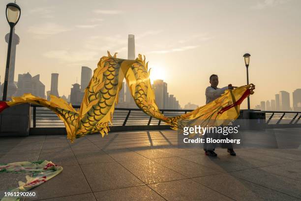 Person flies dragon-shaped kites on the Bund in front of buildings in Pudong's Lujiazui Financial District in Shanghai, China, on Monday, Jan. 29,...
