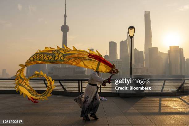 Person flies dragon-shaped kites on the Bund in front of buildings in Pudong's Lujiazui Financial District in Shanghai, China, on Monday, Jan. 29,...