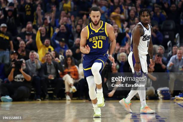 Stephen Curry of the Golden State Warriors reacts after he made a three-point basket on Davion Mitchell of the Sacramento Kings in the first half at...