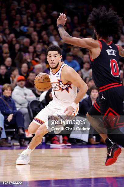 Devin Booker of the Phoenix Suns drives against Coby White of the Chicago Bulls during the game at Footprint Center on January 22, 2024 in Phoenix,...