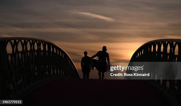 Nicolas Colsaerts of Belgium and his caddie cross a bridge on the 10th hole on Day Two of the Ras Al Khaimah Championship at Al Hamra Golf Club on...