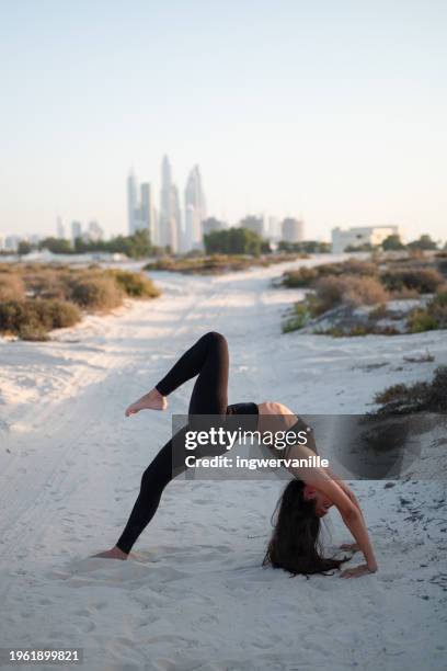 young woman practising yoga with urban skyline view at the background - yoga office arab stock pictures, royalty-free photos & images