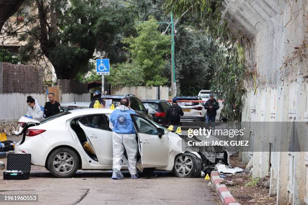 Israeli security and emergency personnel inspect a damaged car following a reported attack near the naval base in the coastal city of Haifa on...