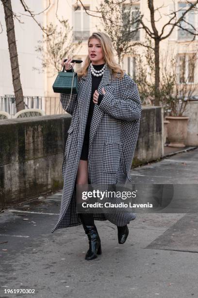 Guest wears black and white pied de poule maxi coat, pearl necklace, black boots, green bag, outside Elie Saab, during the Haute Couture...