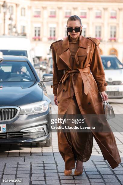 Guest wears brown long dress, brown leather trench coat, brown heels, cream bag, outside Ziad Nakad, during the Haute Couture Spring/Summer 2024 as...