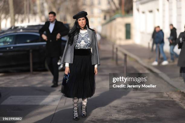 Tina Odjaghian seen wearing black beret hat, silver earrings, silver necklace, white and navy blue butterfly print pattern sweater, white and black...