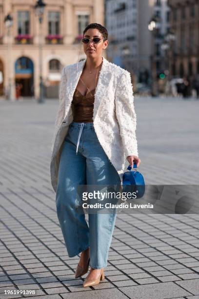 Guest wears brown vinyl top, blue jeans, cream decorated blazer, blue bag, nude heels, outside Ziad Nakad, during the Haute Couture Spring/Summer...