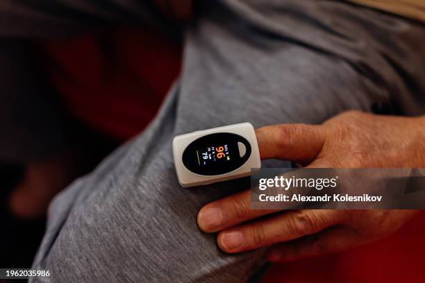 pulse oximeter icon on the middle finger of an elderly man to measure oxygen in the blood. health care for blood saturation test. - kazakhstan coronavirus stock pictures, royalty-free photos & images