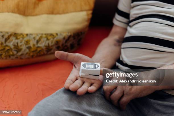 pulse oximeter icon on the middle finger of an elderly man to measure oxygen in the blood. health care for blood saturation test. - kazakhstan coronavirus stock pictures, royalty-free photos & images